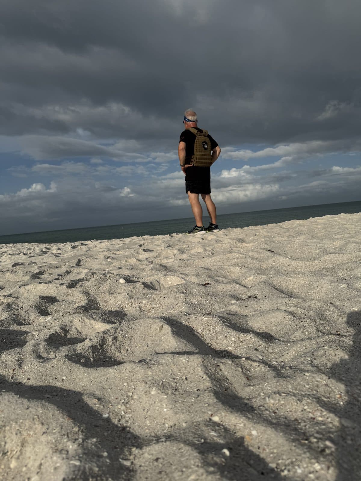 The founder rucking on a Naples beach under storm clouds